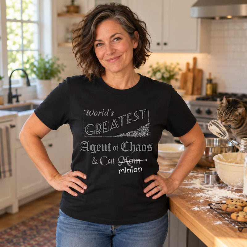 Woman in an Agent of Chaos Cat Mom T-shirt, with a cat on the kitchen counter