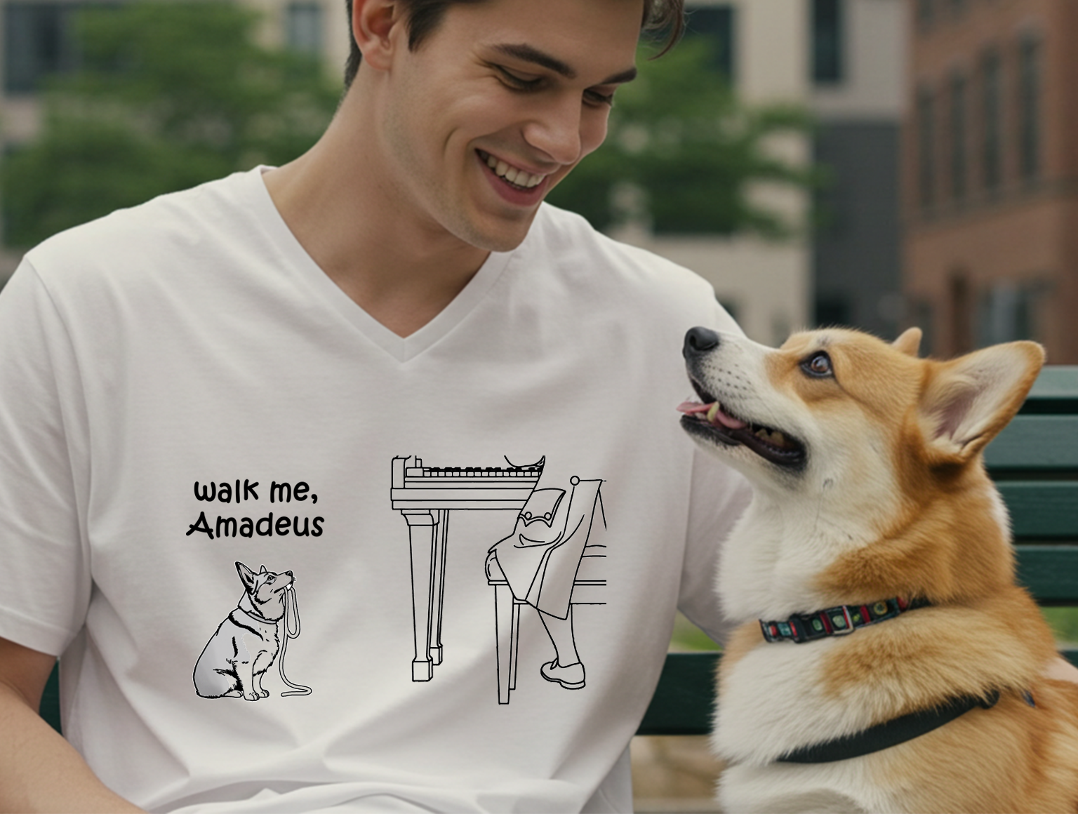 A man wearing a white V-neck t-shirt with a black line art graphic of a corgi and the text 'walk me, Amadeus' sits on a green bench next to a corgi dog.