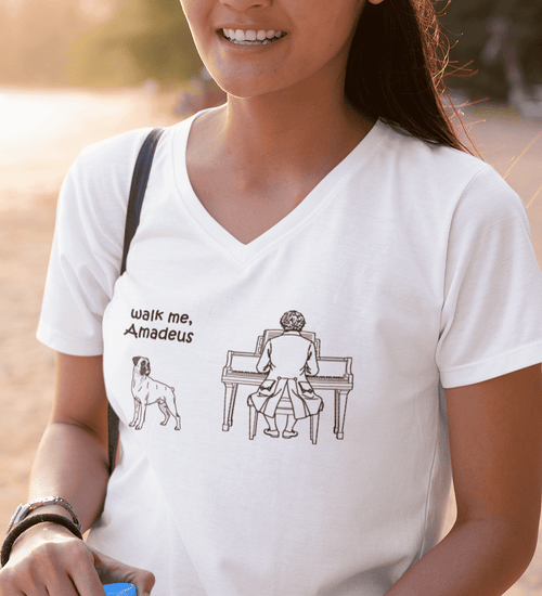 A woman wearing a white V-neck t-shirt with a black graphic print that reads 'walk me, Amadeus' next to an illustration of a