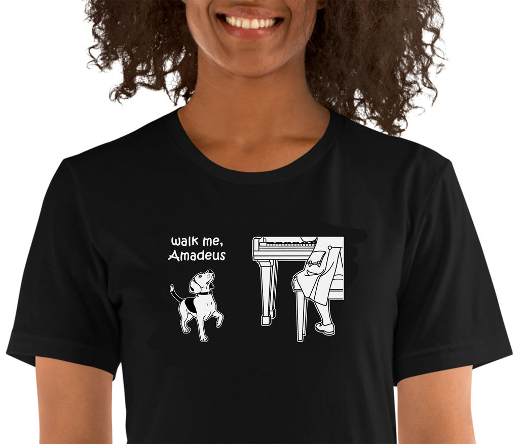 A woman wearing a black short-sleeve t-shirt with a white graphic print that reads 'walk me, Amadeus' next to an illustration of a dog and a pianist.