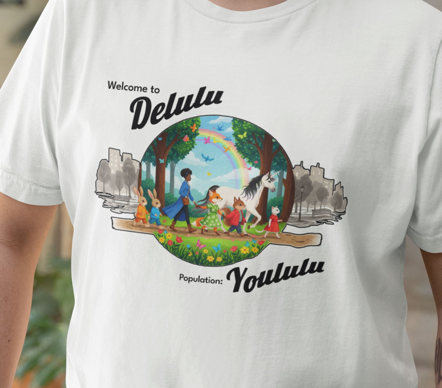 A white short-sleeve t-shirt worn by a person, featuring a colorful graphic print on the front with the text 'Welcome to Delulu' and 'Population: Yoululu' surrounding a circular illustration of children, animals, trees, and a rainbow.