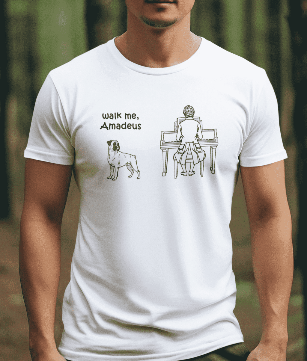 A man wearing a white crew-neck t-shirt with a black line art graphic of a Boxer dog standing beside Mozart at the piano with