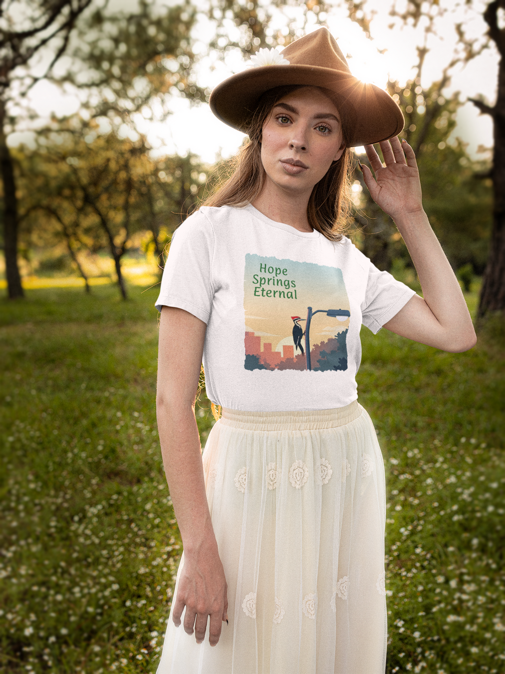 A woman wearing a white graphic t-shirt with 'Hope Springs Eternal' printed on the front, showing a woodpecker pecking at a light pole.
