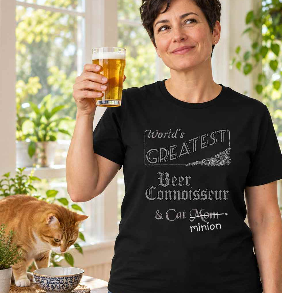 Woman raising a glass of beer beside a cat, wearing a black crew-neck t-shirt that reads, “World’s Greatest Beer Connoisseur & Cat Mom” with “Mom” crossed out and “minion” handwritten below with paw prints.