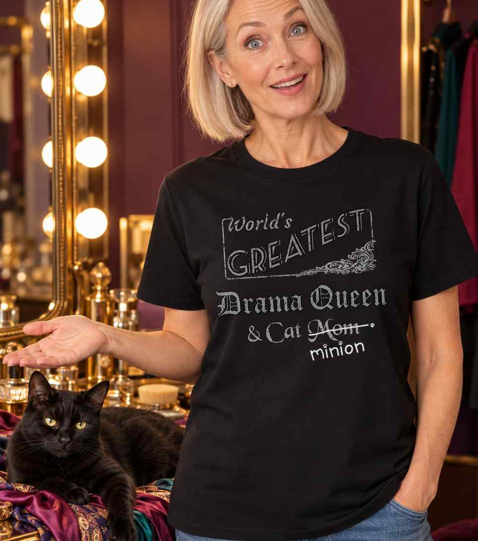 Woman presenting a cat sprawled across scarves in a dressing room, wearing a black crew-neck t-shirt that reads, “World’s Greatest Drama Queen & Cat Mom” with “Mom” crossed out and “minion” handwritten below with paw prints.