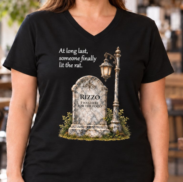 A woman wearing a black V-neck t-shirt with a humorous graphic print: "At long last, someone finally lit the rat." The print features a tombstone reading 'RIZZO - I WAS HERE FOR THE FOOD' next to a vintage street lamp.