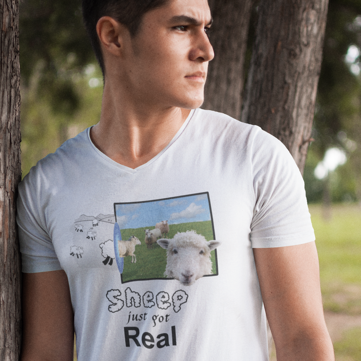 Man wearing a white v-neck t-shirt with cartoon sheep on the left, real sheep on the right, and a portal in between them. The caption reads, 'Sheep Just Got Real'.